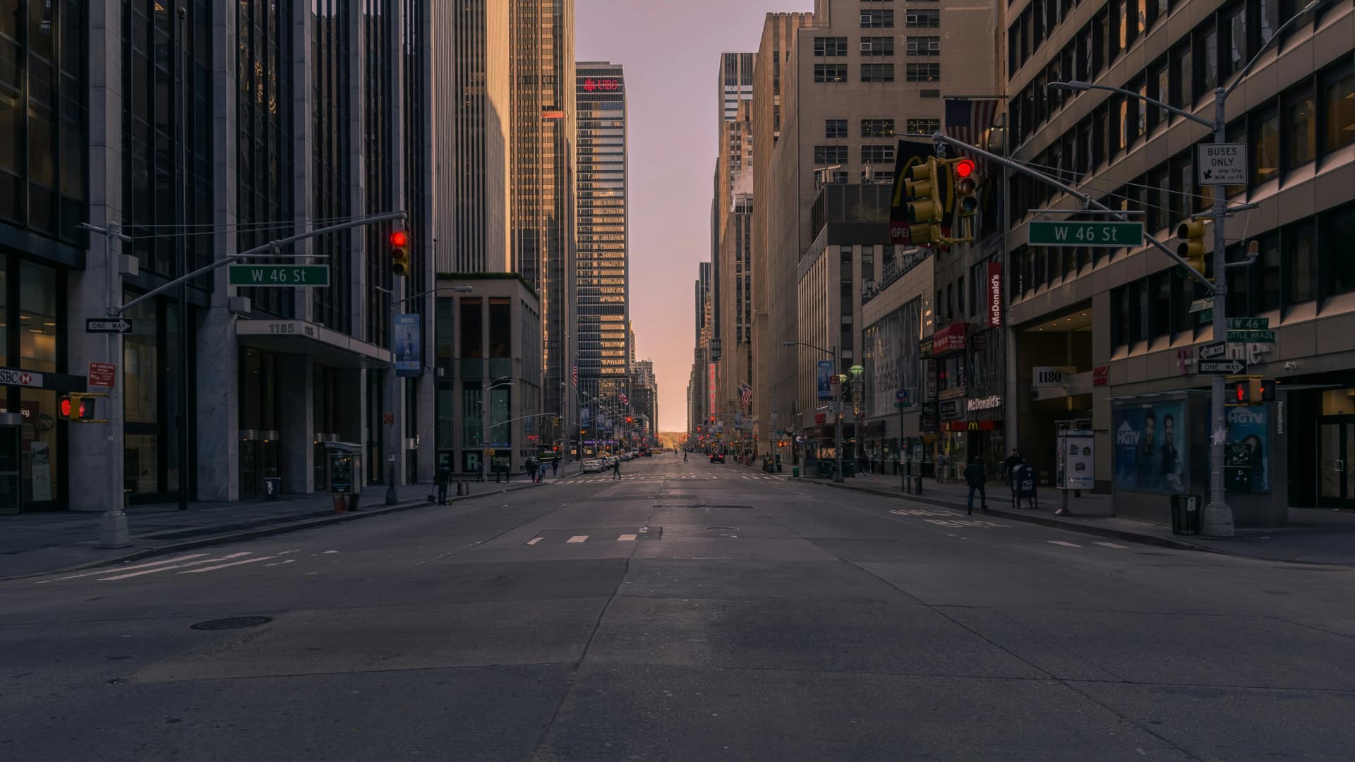 Empty Manhattan avenue at dawn, lined with office towers and traffic lights at the West 46th Street intersection
